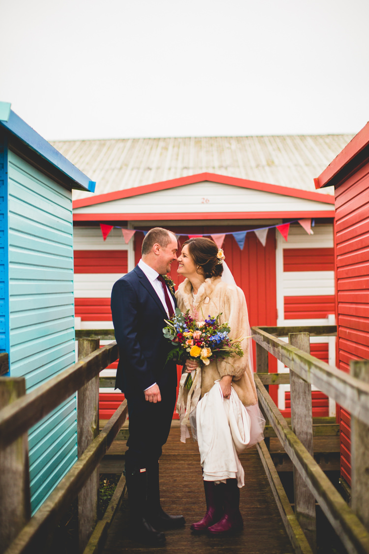 Groom Navy Suit Bride Bridal Floor Length T Shirt Neckline Short Sleeves Multicolour Wild Flower Bouquet Fur Jacket Wellies Colourful Fun Cosy Rainy Sea Wedding http://www.livvy-hukins.co.uk/