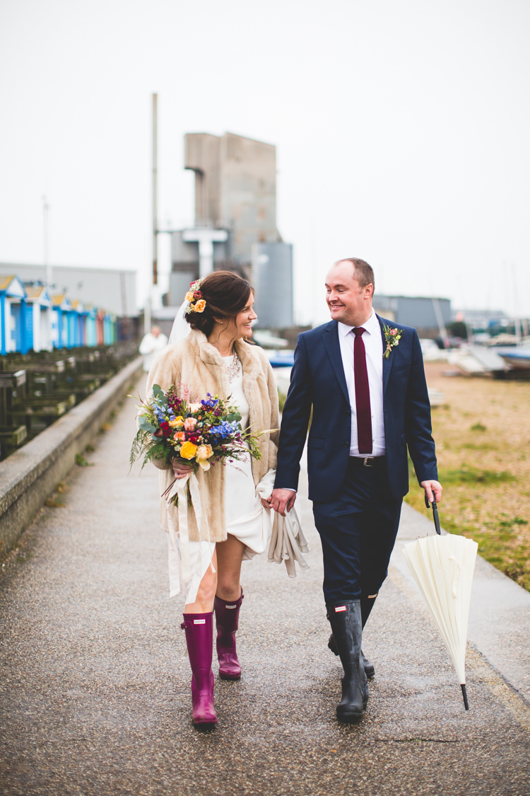 Groom Navy Suit Bride Bridal Floor Length T Shirt Neckline Short Sleeves Multicolour Wild Flower Bouquet Fur Jacket Wellies Umbrella Colourful Fun Cosy Rainy Sea Wedding http://www.livvy-hukins.co.uk/