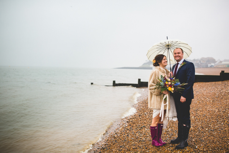 Groom Navy Suit Bride Bridal Floor Length T Shirt Neckline Short Sleeves Multicolour Wild Flower Bouquet Faux Fur Jacket Wellies Umbrella Beach Colourful Fun Cosy Rainy Sea Wedding http://www.livvy-hukins.co.uk/
