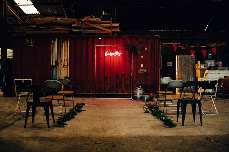Ceremony Room Neon Sign Backdrop Metal Frame Foliage Edgy Raw Industrial Barn Wedding Ideas Greenery Festoon Lights http://www.two-d.co.uk/