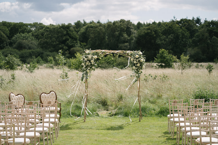 Outdoor Ceremony Arbour Arch Greenery White Floral Flowers Ribbons Relaxed Bohemian Summer Meadow Wedding https://karibellamy.com/