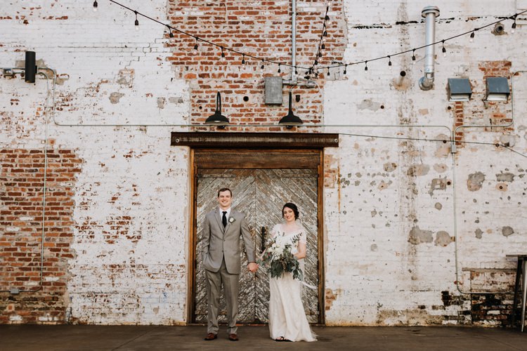 City Urban Georgia Engine Room Exposed Bricks Bride Groom Embrace First Look Green White Bouquet | Bohemian Industrial Oxblood Wedding https://www.lunaleephotos.com/