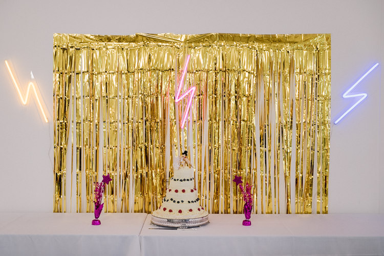 Cake Table Backdrop Gold Curtain Streamers Lightning Bolt Neon Lights Colourful Indie London City Wedding Clissold House West Reservoir Centre https://www.murrayclarke.co.uk/