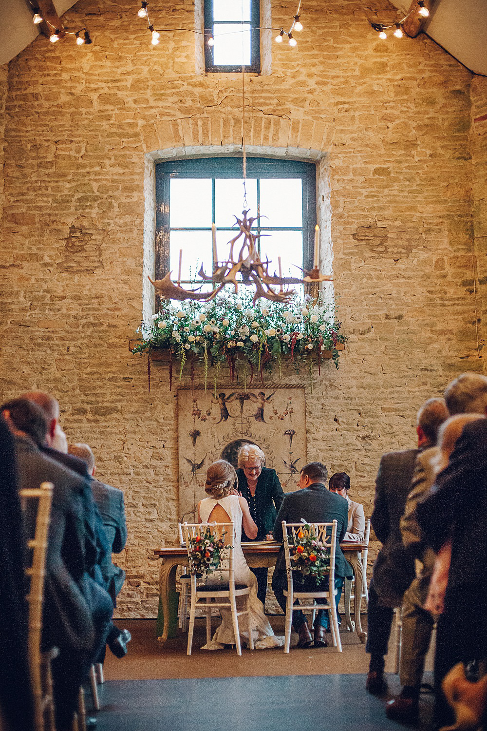 Bride Bridal Lace Boat Neck Cut Out Back Pronovias Neck Dress Tweed Groom Registry Table Floral Runner Chair Backs Navy Merriscourt Barn Wedding Cotswolds Katie de Silva Photography