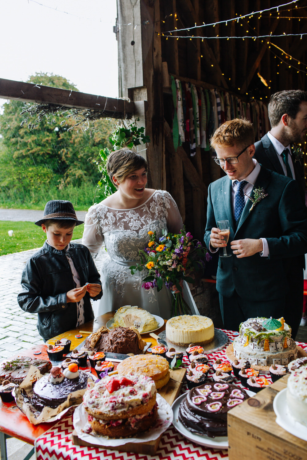 Bride Bridal Tea Length Sleeved Dress Flower Crown Multicoloured Bouquet Flower Crown Groom Bottle Green Suit Three Piece Bake Off Dessert Table Secret Barn Sussex Wedding Rainbow Colourful Yvonne Lishman Photography