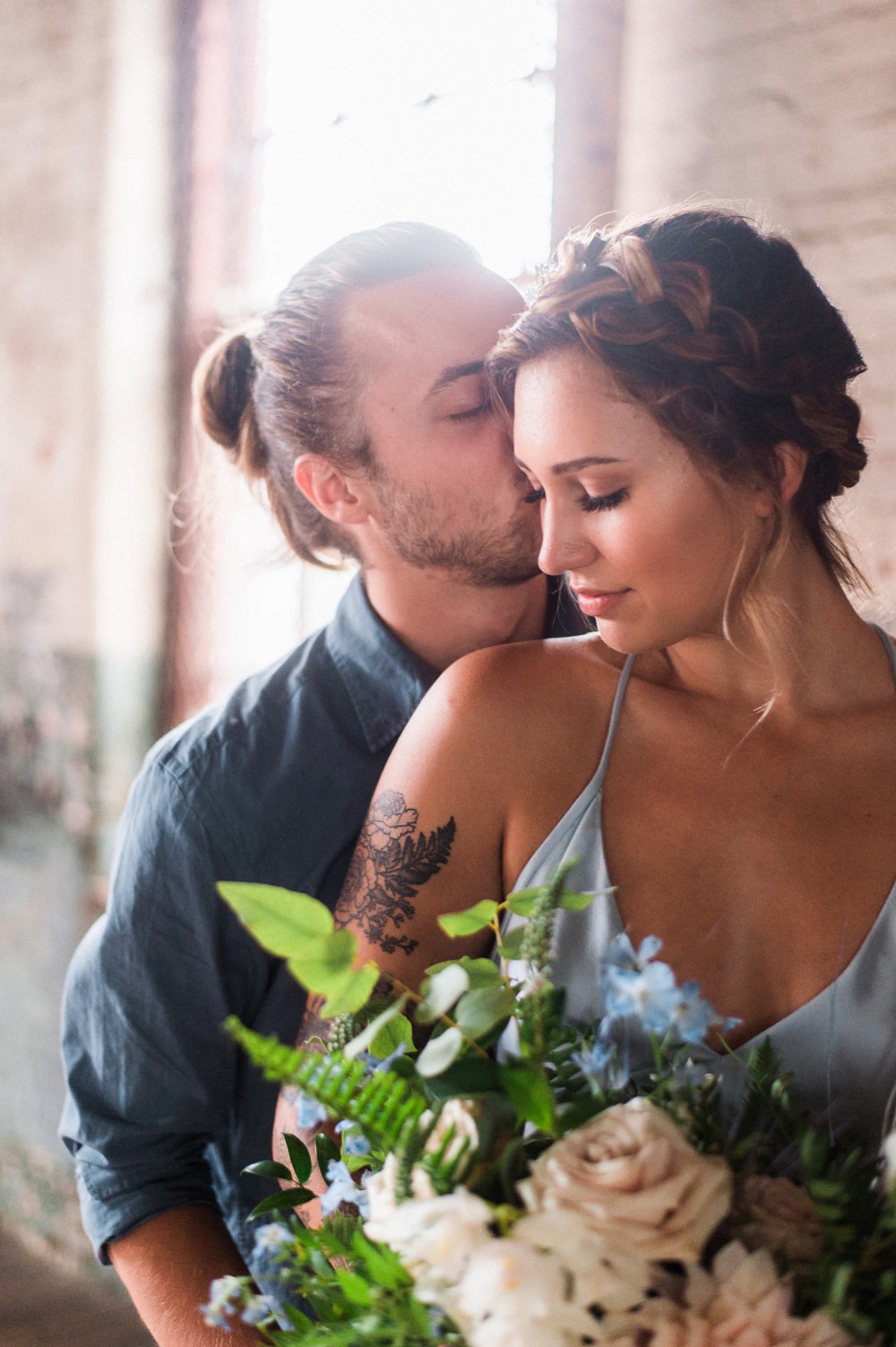 Nature Inspired Styled Shoot Seashell Headpiece Updo Tattooed Bride Blue Dress Casual Groom Blue Shirt Pastel Bouquet Kiss | Ocean Wedding Ideas Industrial Rachel Watkinson Photography