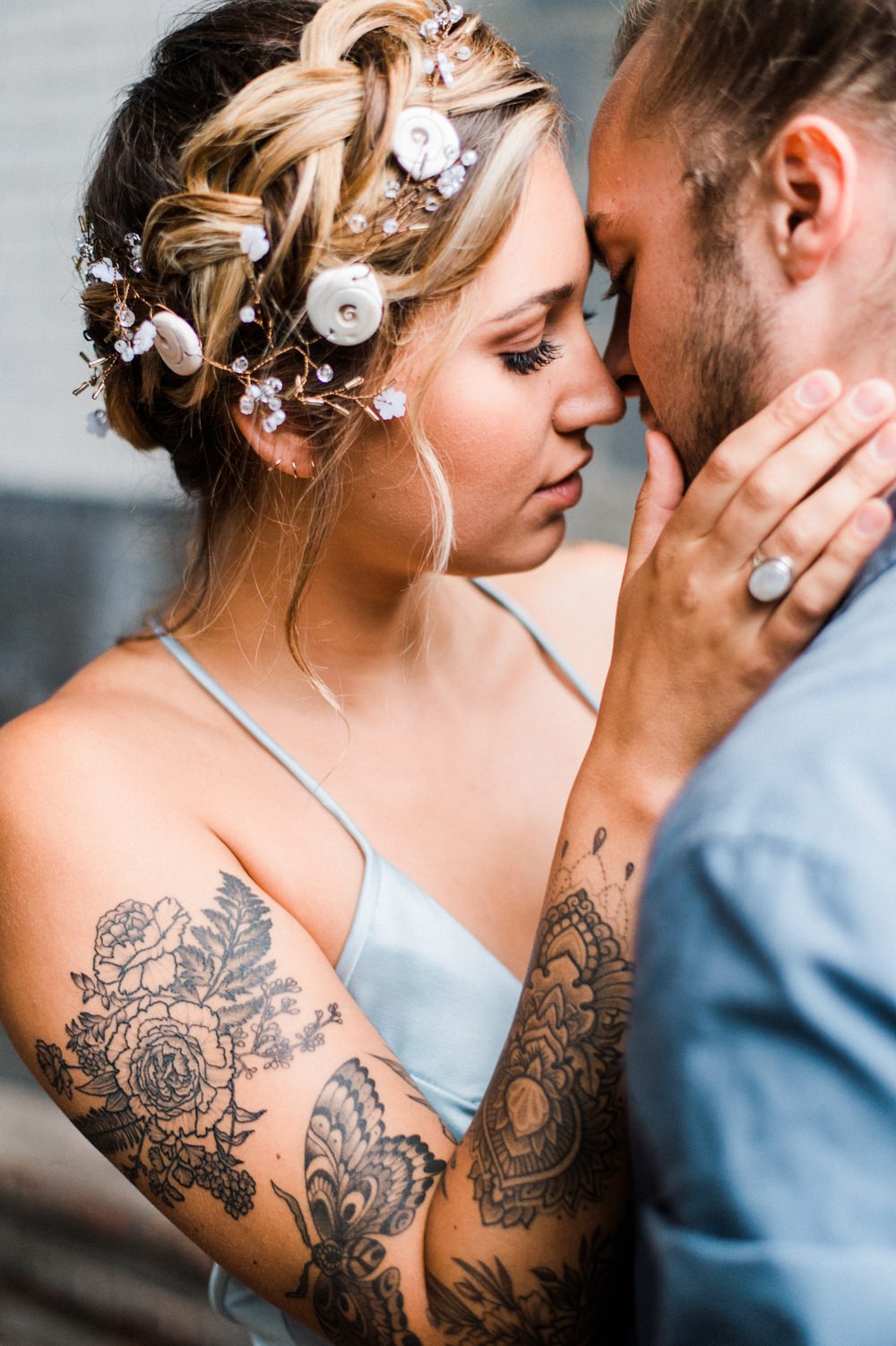 Nature Inspired Styled Shoot Seashell Headpiece Updo Tattooed Bride Blue Dress Casual Groom Blue Shirt Kiss | Ocean Wedding Ideas Industrial Rachel Watkinson Photography