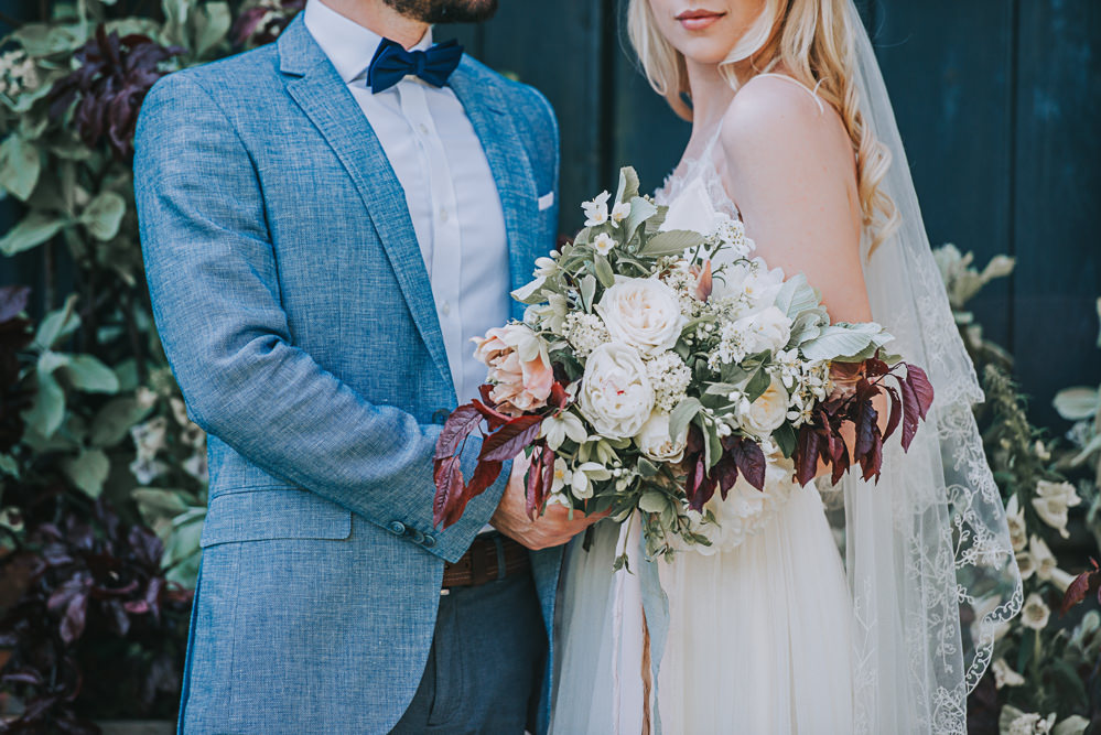 Secret Dresshouse Ethereal Bride Bridal Gown Blue Linen Jacket Bow Tie Groom Leaf Foliage Flower Florals River Romance Wedding Ideas Mindy Coe Photography