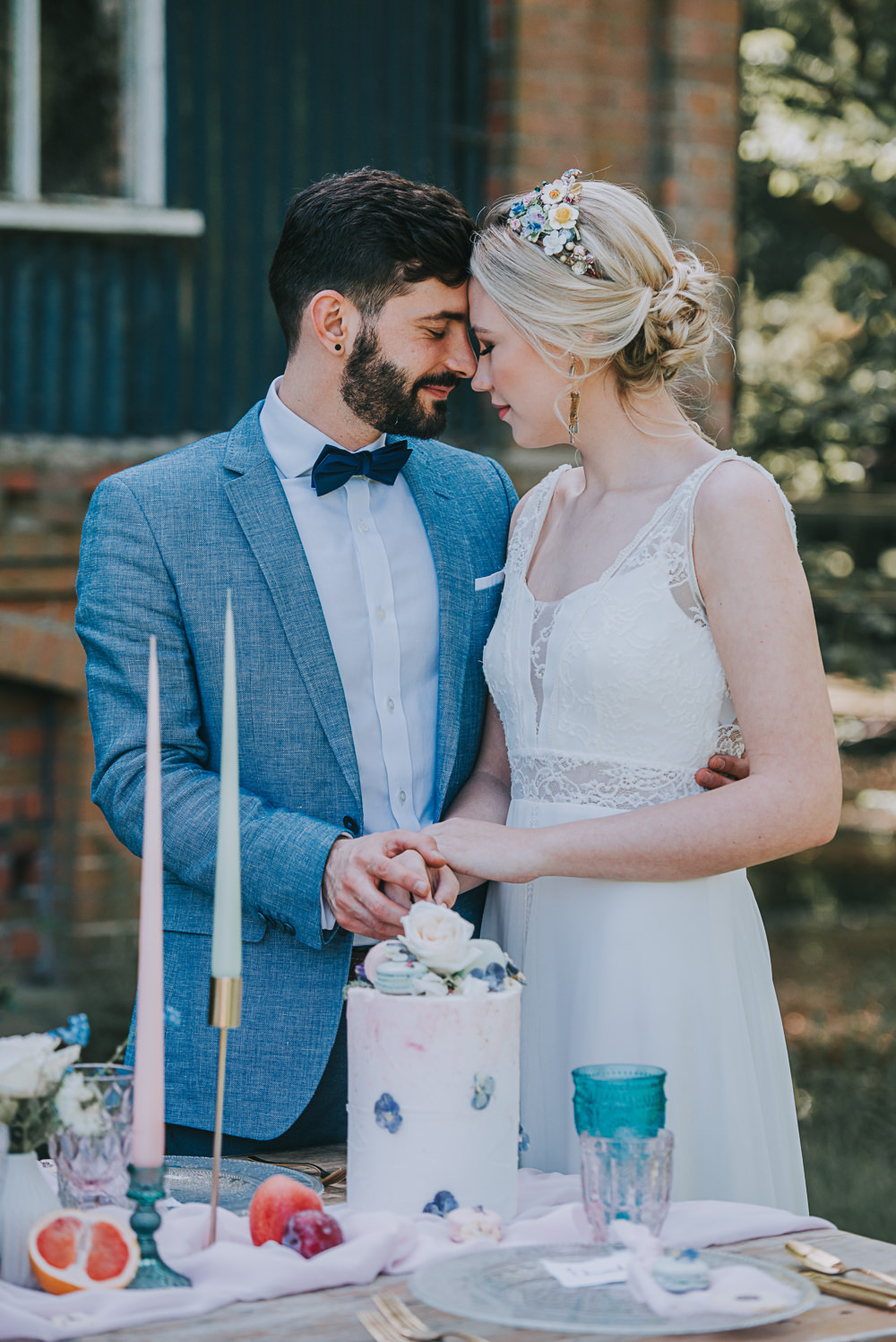 Secret Dresshouse Ethereal Bride Bridal Gown Storm Hurricane Candles Lanterns Leaf Foliage Cake Cutting Buttercream Macaron Blue Linen Jacket Bow Tie Groom River Romance Wedding Ideas Mindy Coe Photography