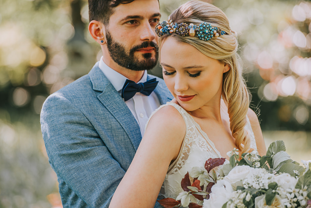 Secret Dresshouse Ethereal Bride Bridal Gown Storm Hurricane Candles Lanterns Leaf Foliage Flower Florals Bouquet Jewelled Crown Blue Linen Jacket Bow Tie Groom River Romance Wedding Ideas Mindy Coe Photography