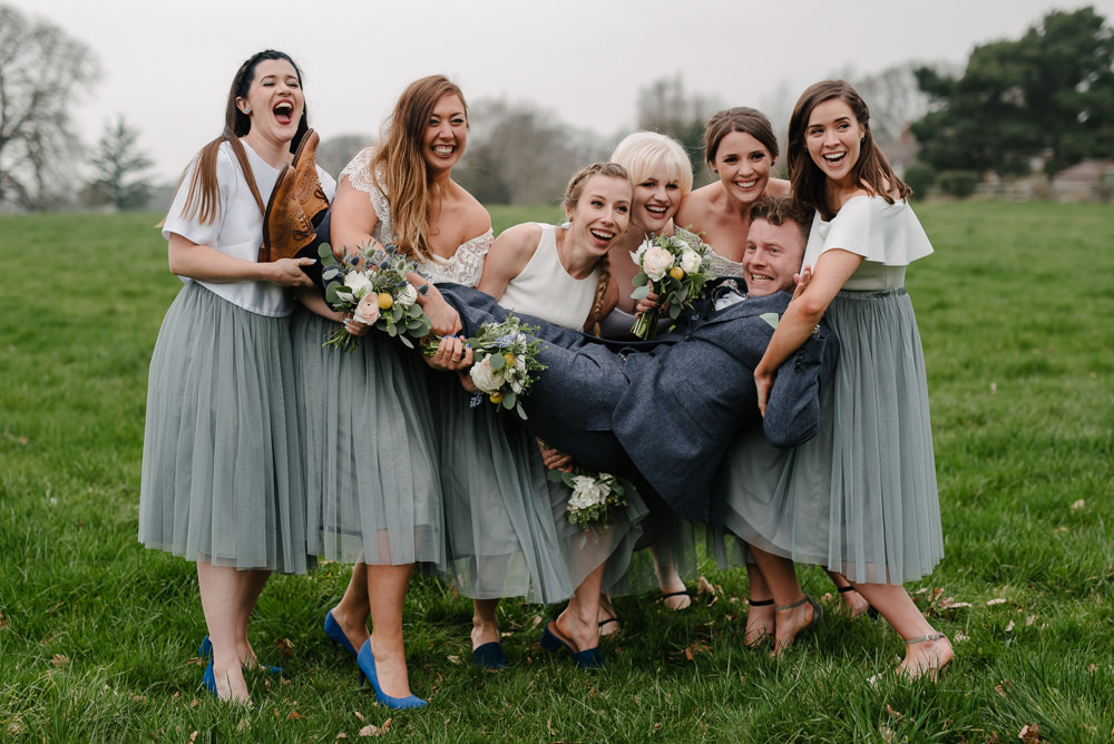 Outdoor Farm Field Marquee Bridesmaids White Grey Separates Group Holding Groom | Rustic and Relaxed Spring Tipi Wedding Inbetween Days Photography