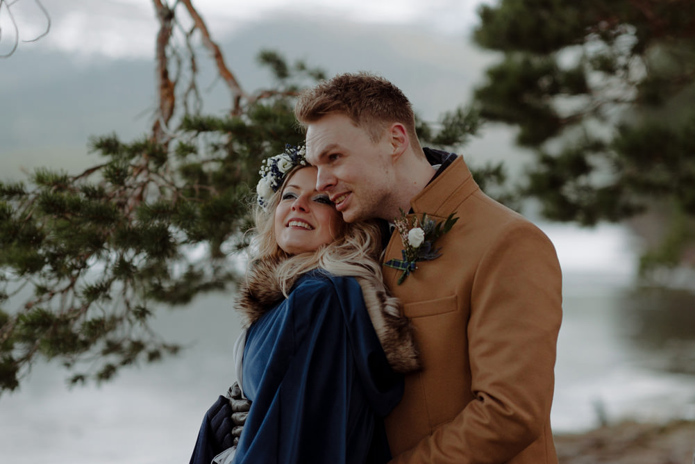 Forest Trees Castle Loch Bride Groom Blue Dress White Bouquet Floral Crown Cape Tan Coat | Intimate Winter Outdoor Scotland Wedding Christopher Ian Photography