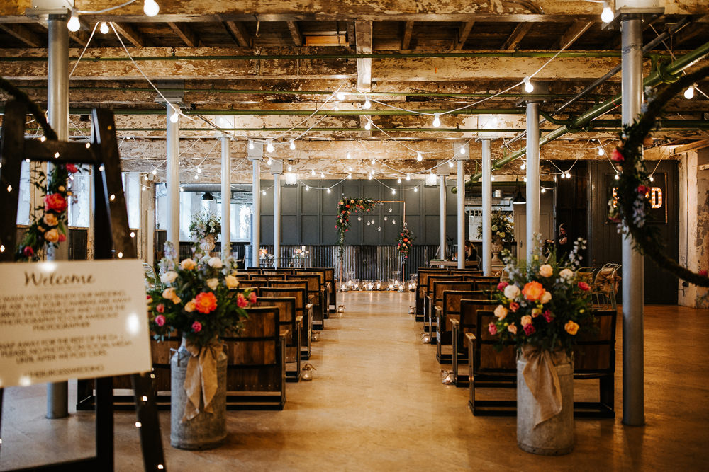 Ceremony Warehouse Industrial Festoon Lights Flowers Backdrop Arch Aisle Holmes Mill Wedding Emilie May Photography