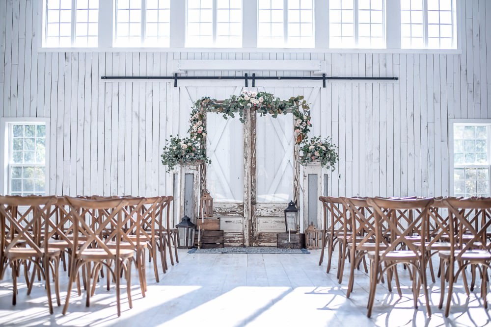 Ceremony Wooden Cross Back Chairs Floral Greenery Foliage Archway Storm Lanterns White Sparrow Barn Wedding White Blue Ideas Si Creative Photography