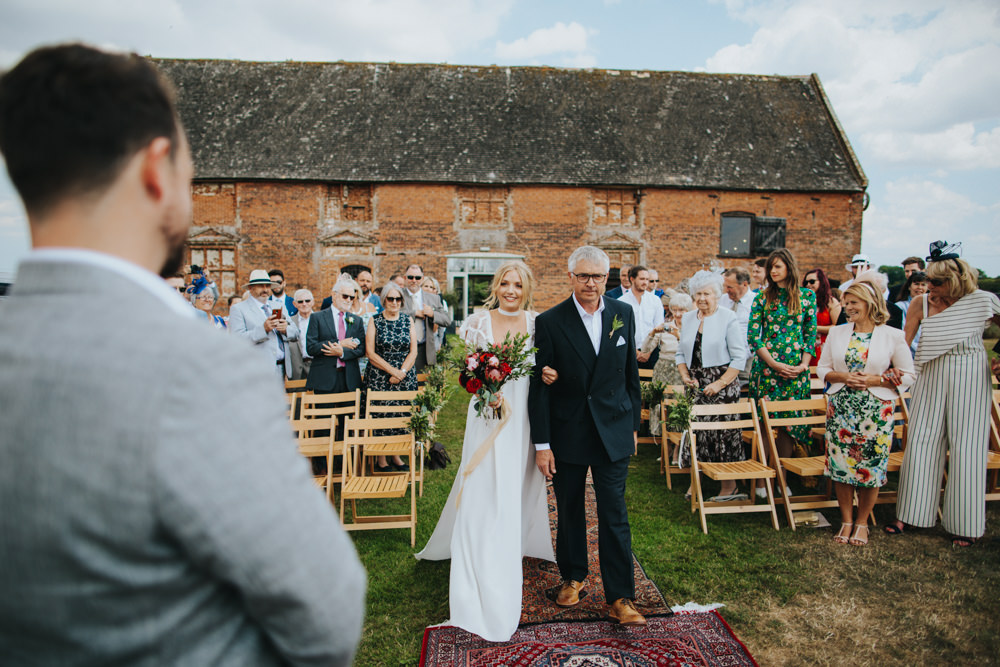 Aisle Ceremony Outdoor Persian Rug Wooden Triangle Backdrop Palm Plants Godwick Great Barn Wedding Joshua Patrick Photography