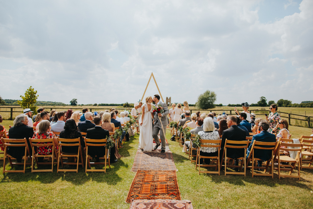 Aisle Ceremony Outdoor Persian Rug Wooden Triangle Backdrop Palm Plants Godwick Great Barn Wedding Joshua Patrick Photography