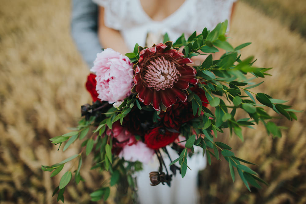 Bouquet Flowers Bride Bridal Red Greenery Foliage Ribbons Peony Peonies Rose Proteas Pink Godwick Great Barn Wedding Joshua Patrick Photography