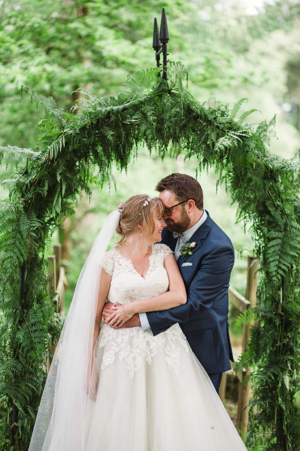 Bride Bridal Ballerina Length Dress Lace Sleeves Navy Suit Groom Veil Greenery Foliage Archway Middle Coombe Farm Wedding Emma Stoner Photo