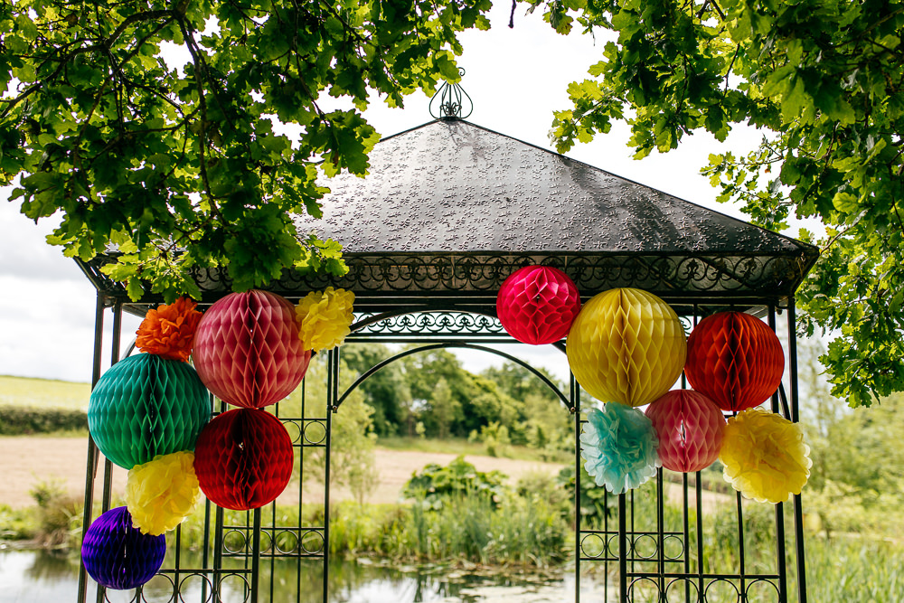 Outdoor Ceremony Arch Lanterns Pom Poms Rainbow Colourful Decor Backdrop Ash Barton Estate Wedding Jordanna Marston Photography