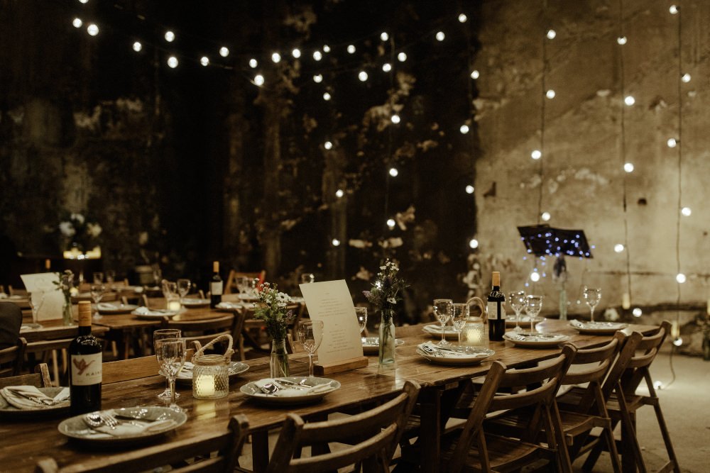 Long Wooden Tables Chairs Flowers Bottles Festoon Lights Lighting Brunel Museum Wedding Olivia and Dan Photography