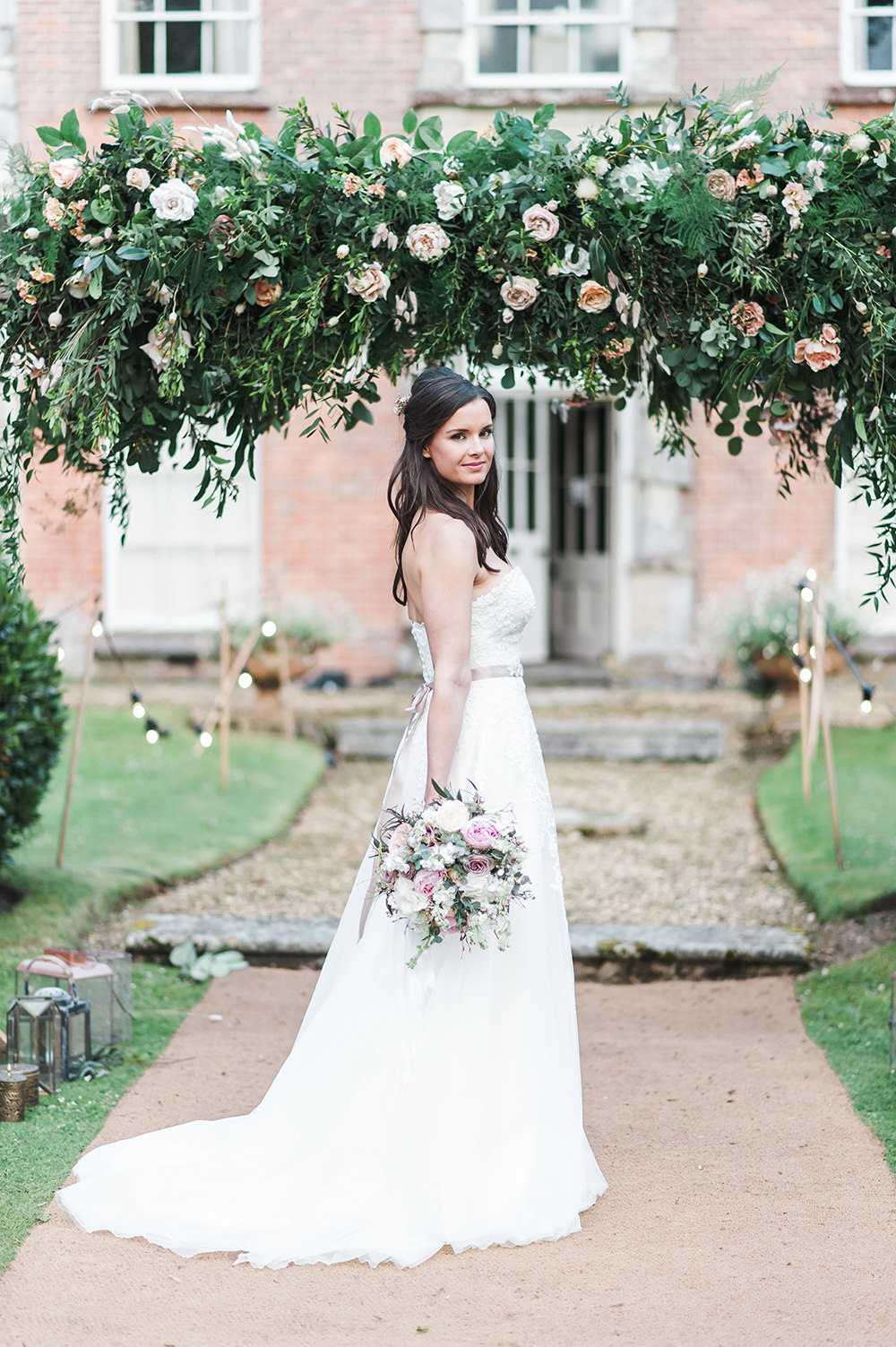 Bride Bridal Gown Dress Strapless Sweetheart Neckline Ribbon Belt Pink Foliage Greenery Rose Arch Archway Edmondsham House Wedding Darima Frampton Photography