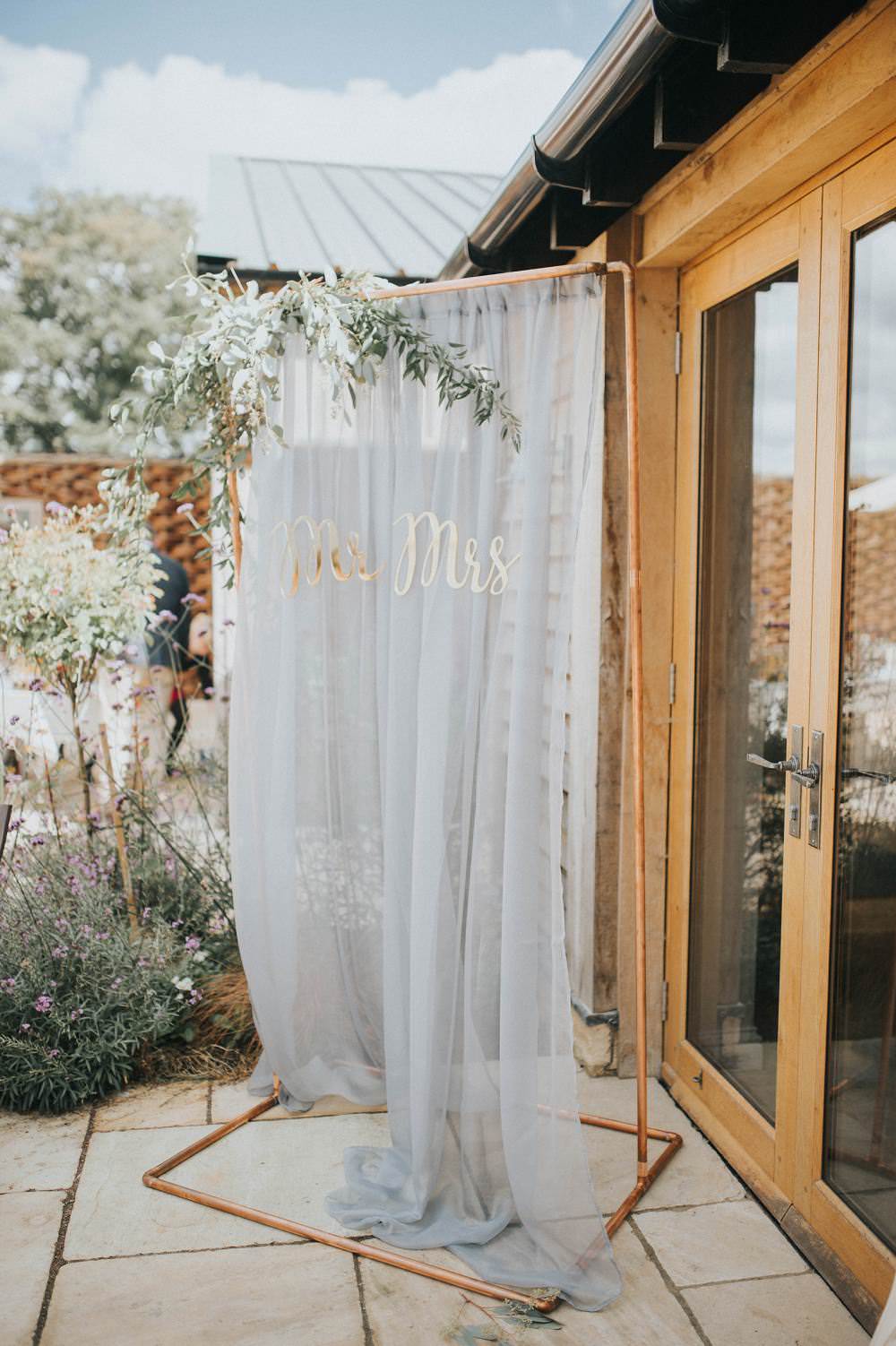 Backdrop Sign Photo Booth Copper Pipe Metal Silk Fabric Grey Mr Mrs Gold Letters Foliage Eucalyptus Boho Greenery Barn Wedding Kerry Diamond Photography