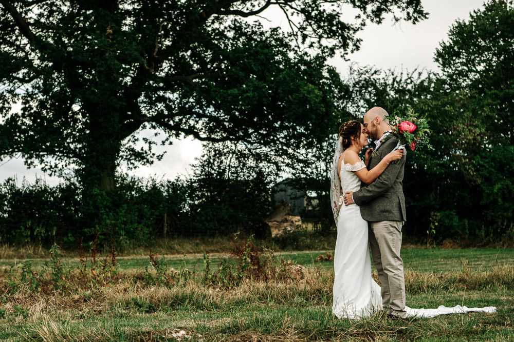 Bride Bridal Dress Gown Lace Detail Drop Cold Shoulder Ribbon Bow Sleeveless Tweed Suit Waistcoat Groom Floral Veil Stanford Farm Wedding Andy Griffiths Photography