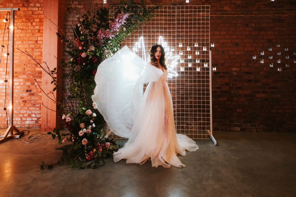 Flower Installation Backdrop Neon Sign Greenery Foliage Metal Bride Bridal Dress Gown Train Tulle Romantic Wedding Ideas Neon Lighting Kate McCarthy Photography