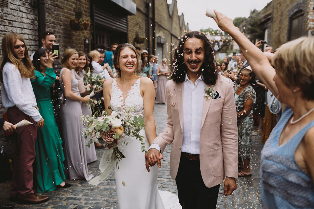Bride Bridal Sleeveless V Neck Fit and Flare Train Pronovias Dress Gown Pink Jacket Reiss Groom Wild Bouquet Loose Handtied Rose Confetti Tram House Wedding Luke Hayden Photography