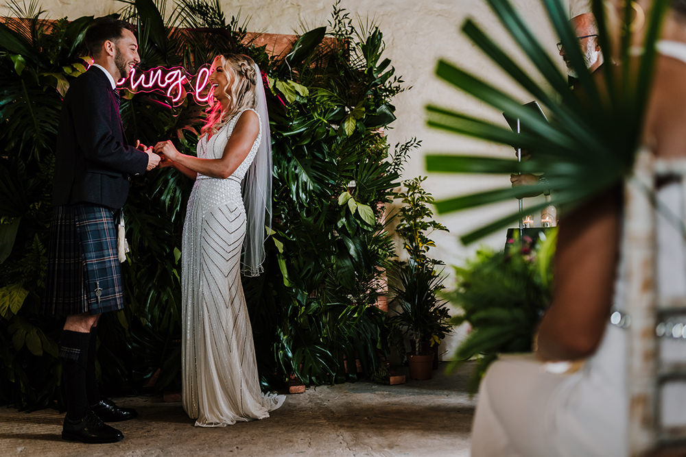 Bride Bridal Beaded Embellished V Neck Dress Gown Succulents Bouquet Kilt Groom Neon Young Love Sign Greenery Backdrop Tropical Luxe Wedding Burfly Photography