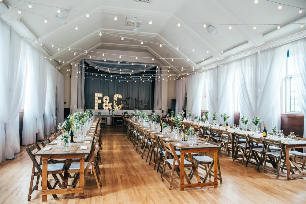 Festoon Lights Trestle Tables Long Wooden Chairs Chichester Hall Wedding Three Flowers Photography