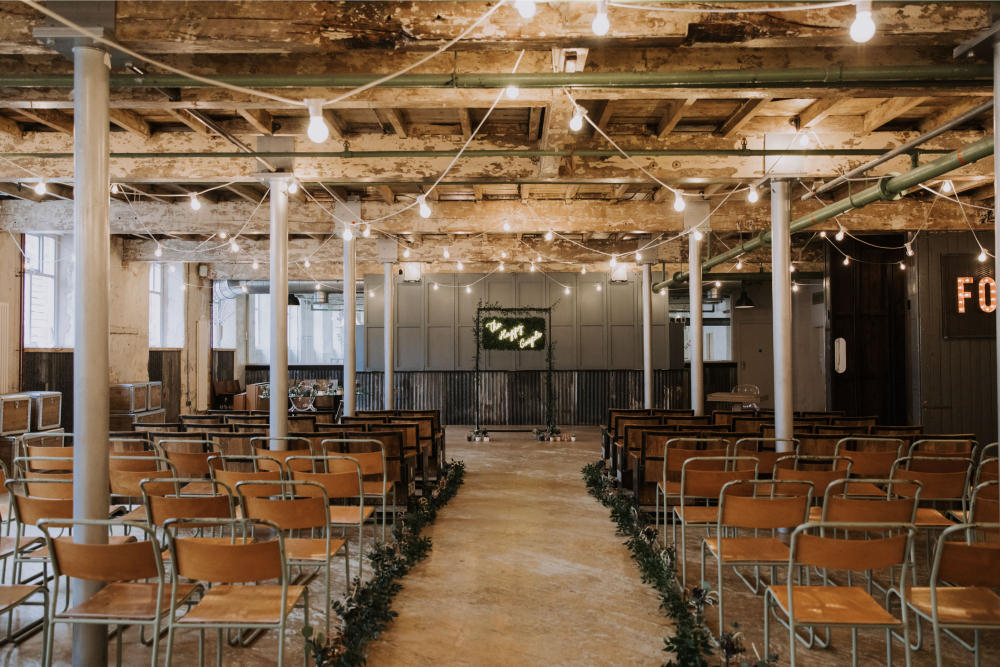 Industrial Venue Ceremony Decor Festoon Lights Backdrop Neon Sign Frame Arch Greenery Foliage Holmes Mill Wedding Siobhan Amy Photography