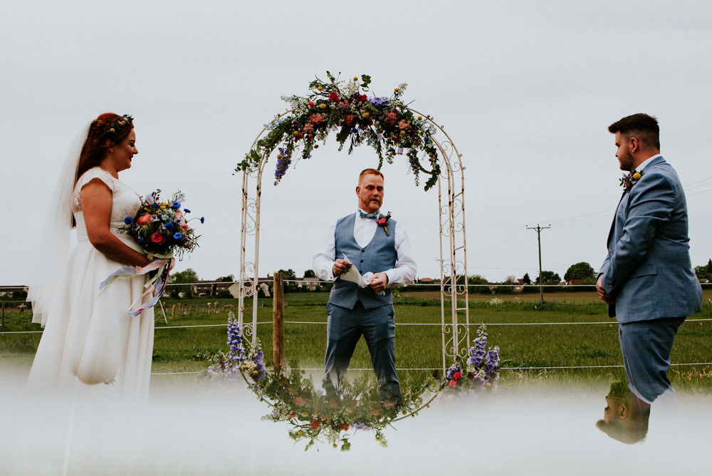 Bride Bridal V Neck Cap Sleeve Tea Length Dress Gown Flower Crown Blue Grey Suit Groom Ceremony Arch Flowers Floral Bert's Barrow Wedding Shutter Go Click Photography