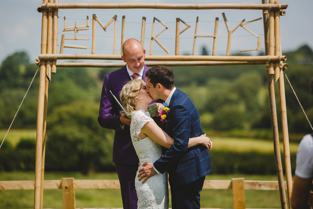 Bride Bridal High Neck Cap Sleeve Lace Fitted Dress Gown Bow Tie Waistcoat Groom Wes Anderson Camp Sign Backdrop East Keswick Village Hall Wedding James & Lianne Wedding Photography