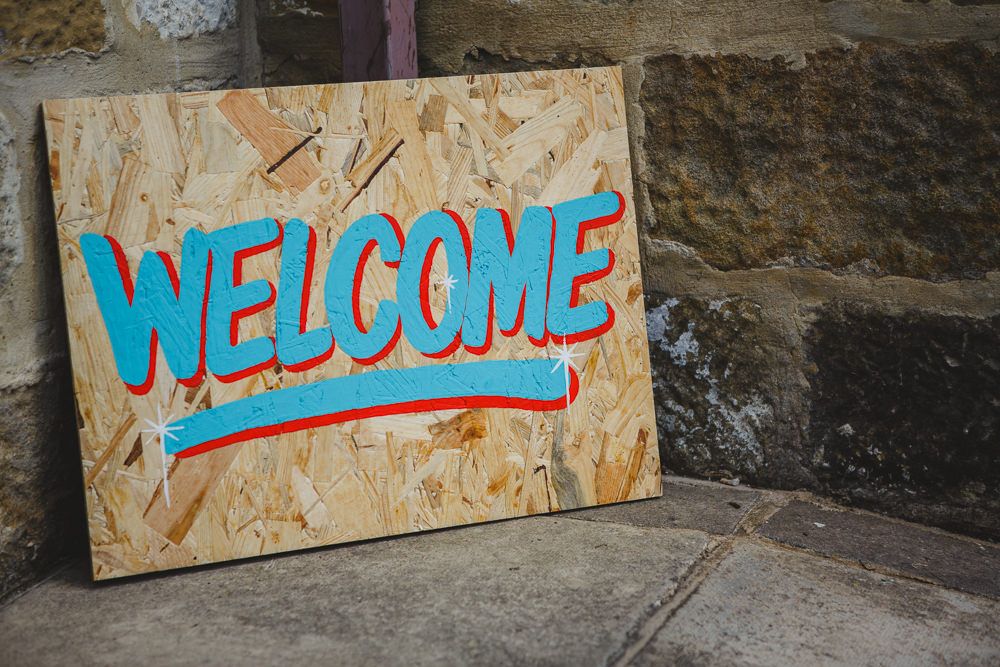 Welcome Painted Sign Wood East Keswick Village Hall Wedding James & Lianne Wedding Photography