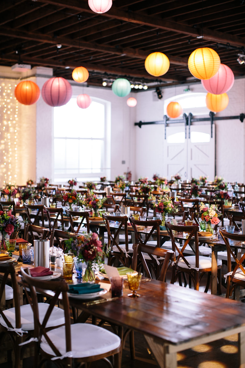 Long Tables Wooden Cross Back Chairs Colourful Lanterns Flowers Napkins Bridal Jumpsuit Wedding Emily Jarrett Photography