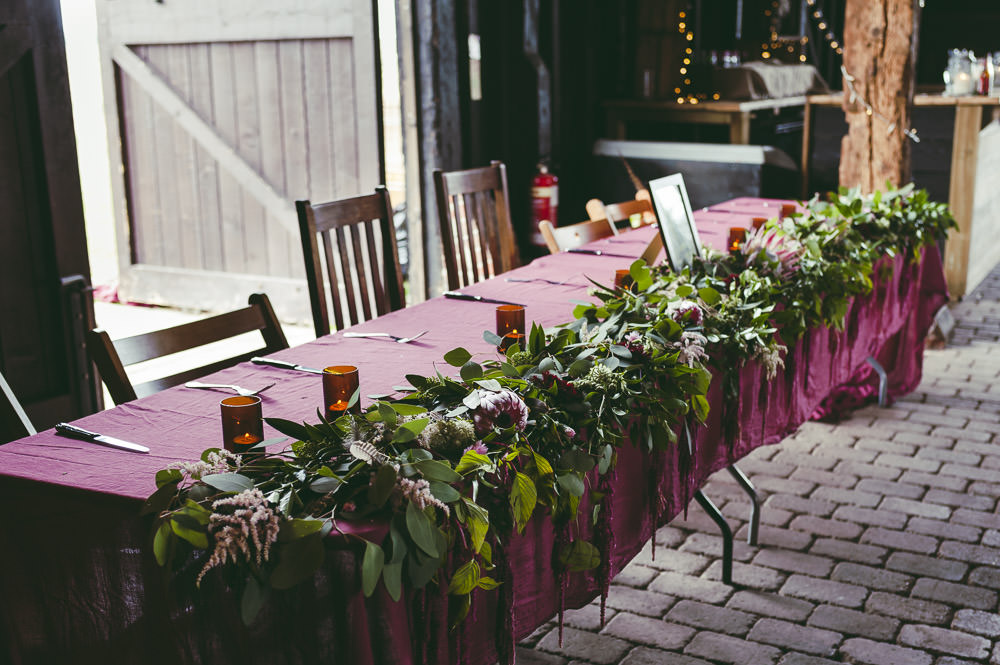 Top Table Red Burgundy Table Cloths Greeenery Foliage Protea Flowers Kingshill Barn Wedding Sandra Reddin Photography
