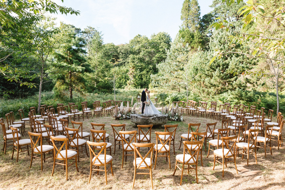 Boconnoc Wedding Debs Alexander Photography Ceremony Woodland Outdoor Circle Round Chairs Flowers Pampas Grass Palm Leaves Dahlias Aisle