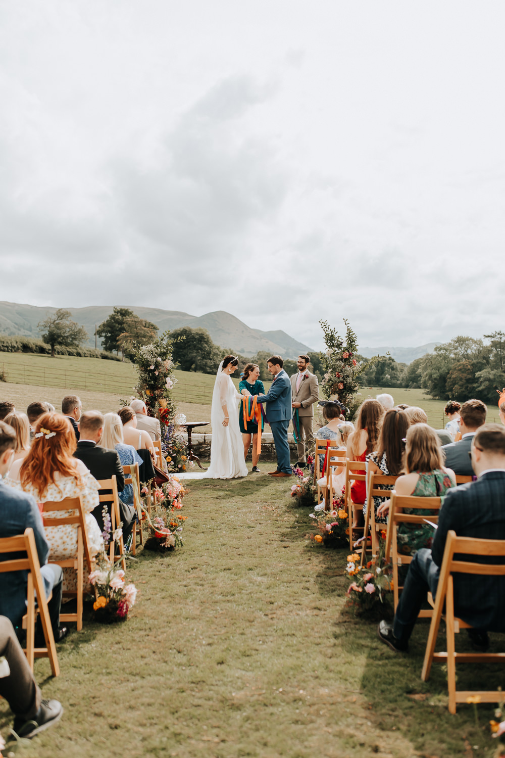 Wooden Chairs Rainbow Ribbons Flowers Aisle Ceremony Outdoors Plas Dinam Wedding Wyldbee Photography