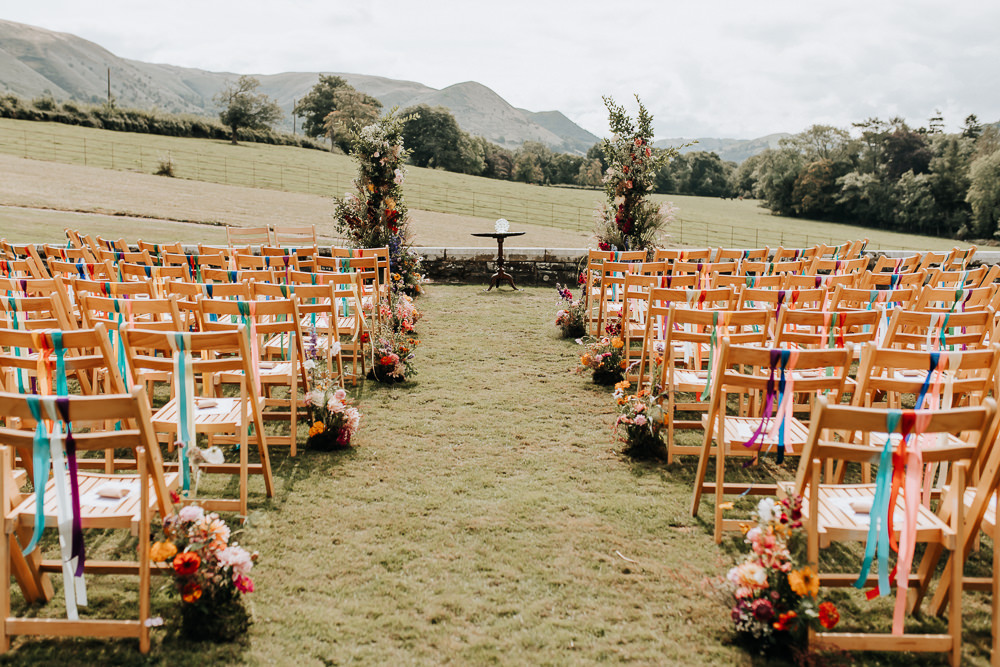 Wooden Chairs Rainbow Ribbons Flowers Aisle Ceremony Outdoors Plas Dinam Wedding Wyldbee Photography