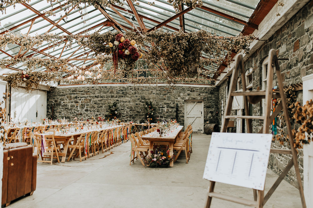 Glass House Conservatory Reception Wooden Chairs Rainbow Ribbons Long Tables Flowers Decor Plas Dinam Wedding Wyldbee Photography