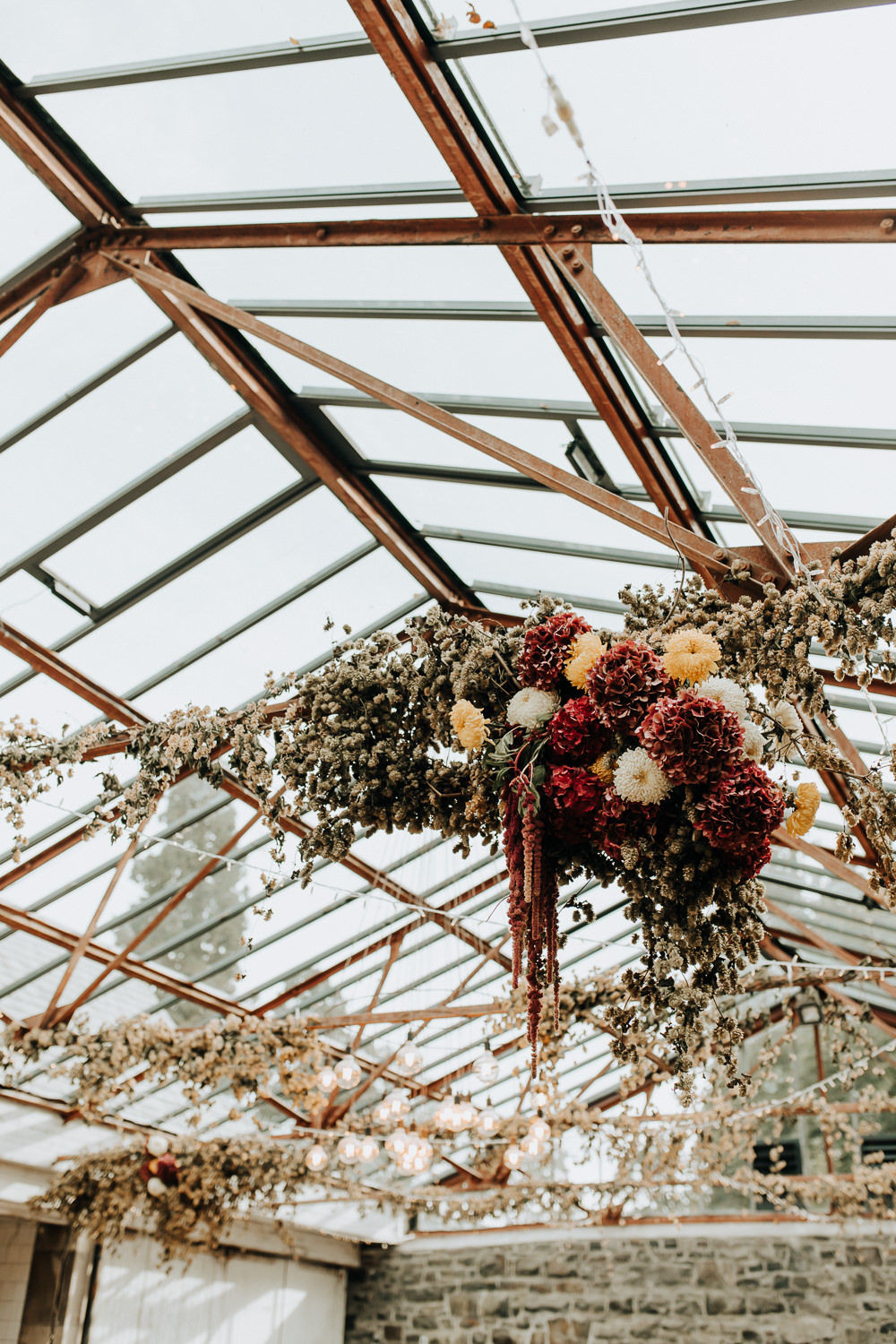 Glass House Conservatory Reception Wooden Chairs Rainbow Ribbons Long Tables Flowers Decor Plas Dinam Wedding Wyldbee Photography