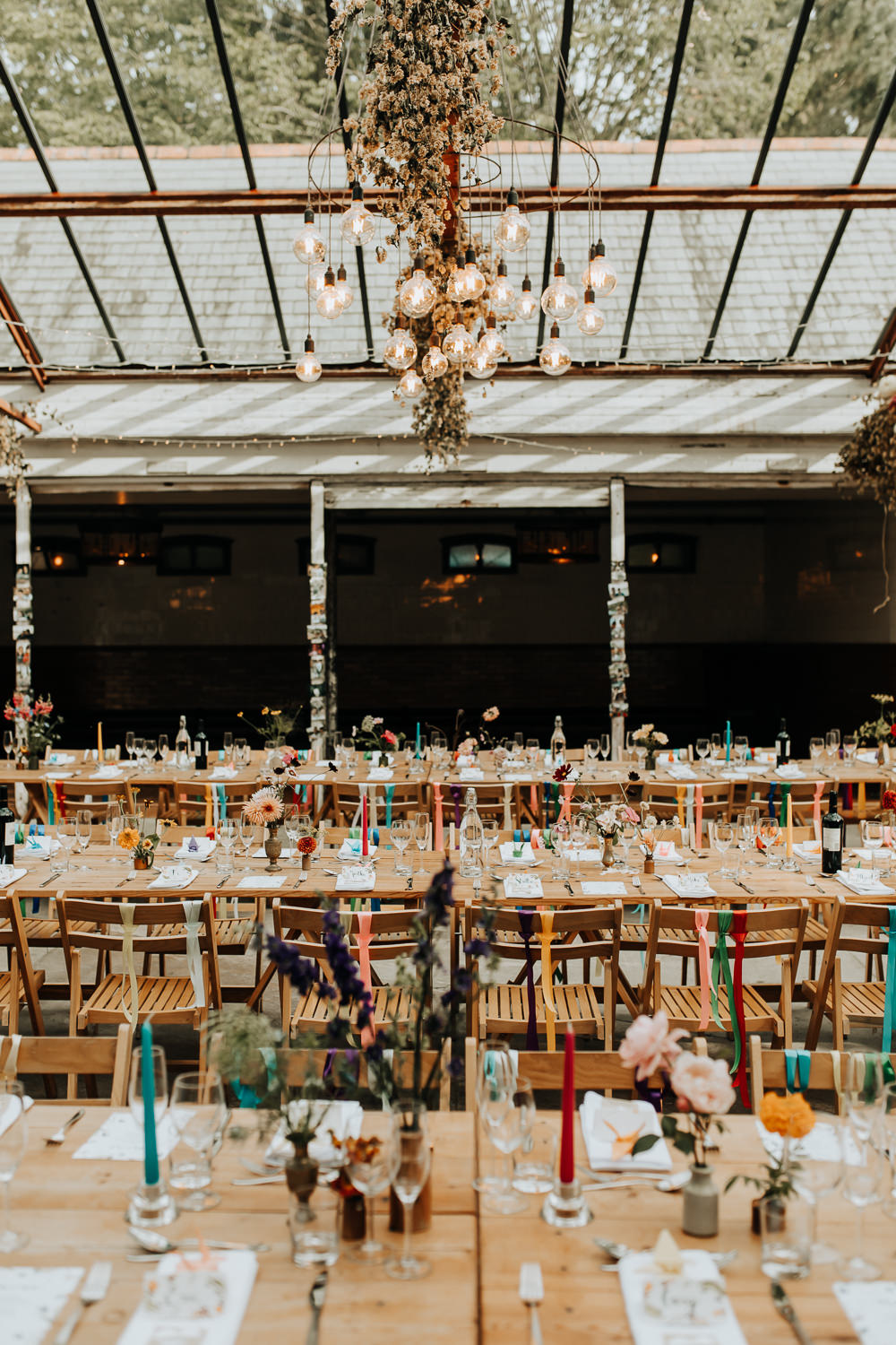 Glass House Conservatory Reception Wooden Chairs Rainbow Ribbons Long Tables Flowers Decor Plas Dinam Wedding Wyldbee Photography