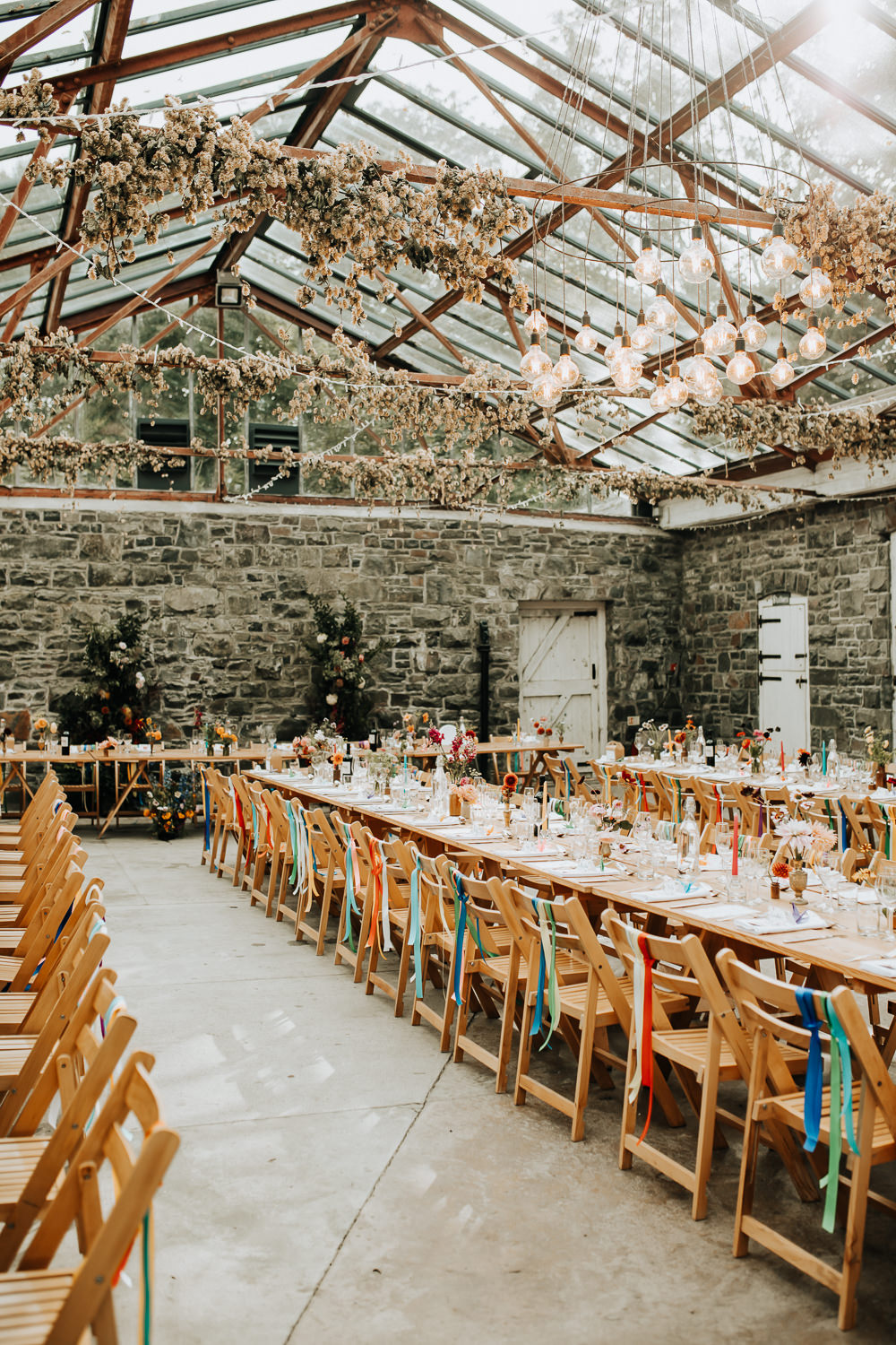 Glass House Conservatory Reception Wooden Chairs Rainbow Ribbons Long Tables Flowers Decor Plas Dinam Wedding Wyldbee Photography