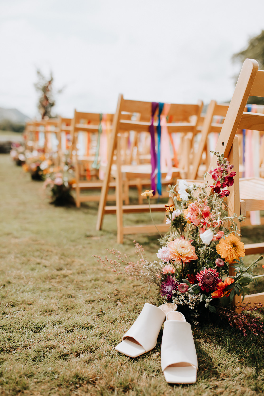 Wooden Chairs Rainbow Ribbons Flowers Aisle Ceremony Outdoors Shoes Plas Dinam Wedding Wyldbee Photography