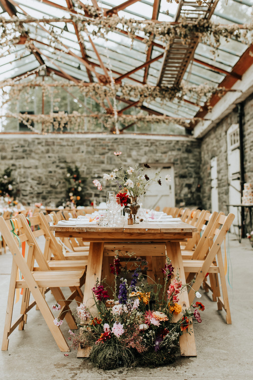Glass House Conservatory Reception Wooden Chairs Rainbow Ribbons Long Tables Flowers Decor Plas Dinam Wedding Wyldbee Photography
