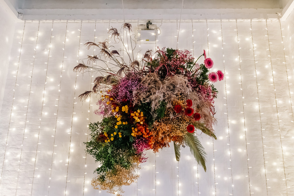 Ceremony Flowers Colourful Fairy Light Wall Suspended Hanging London Warehouse Wedding Kristian Leven Photography