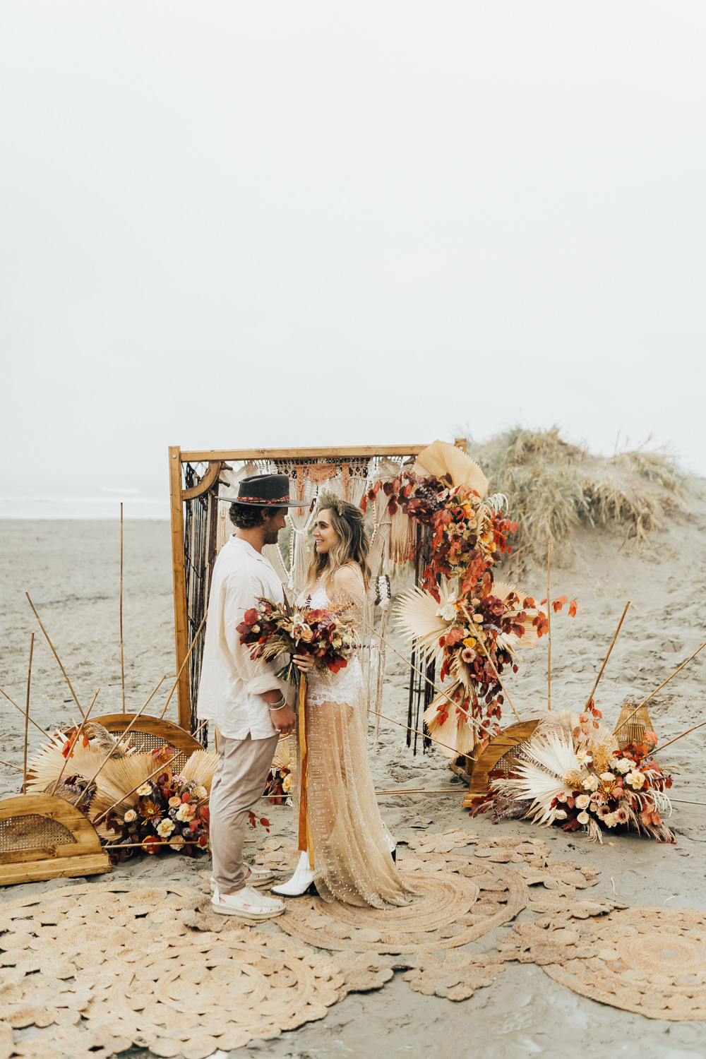 Boho Beach Elopement Rebecca Carpenter Photography Flower Arch Backdrop Flower Arrangement Orange Rose Palm Leaf