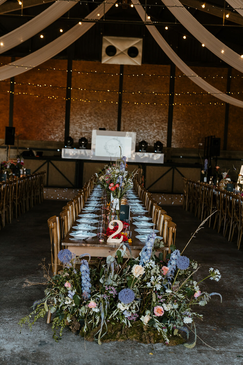 Long Wooden Tables Barn Decor Flowers Meadow Indian Lithuanian Wedding Ellie Gillard Photography