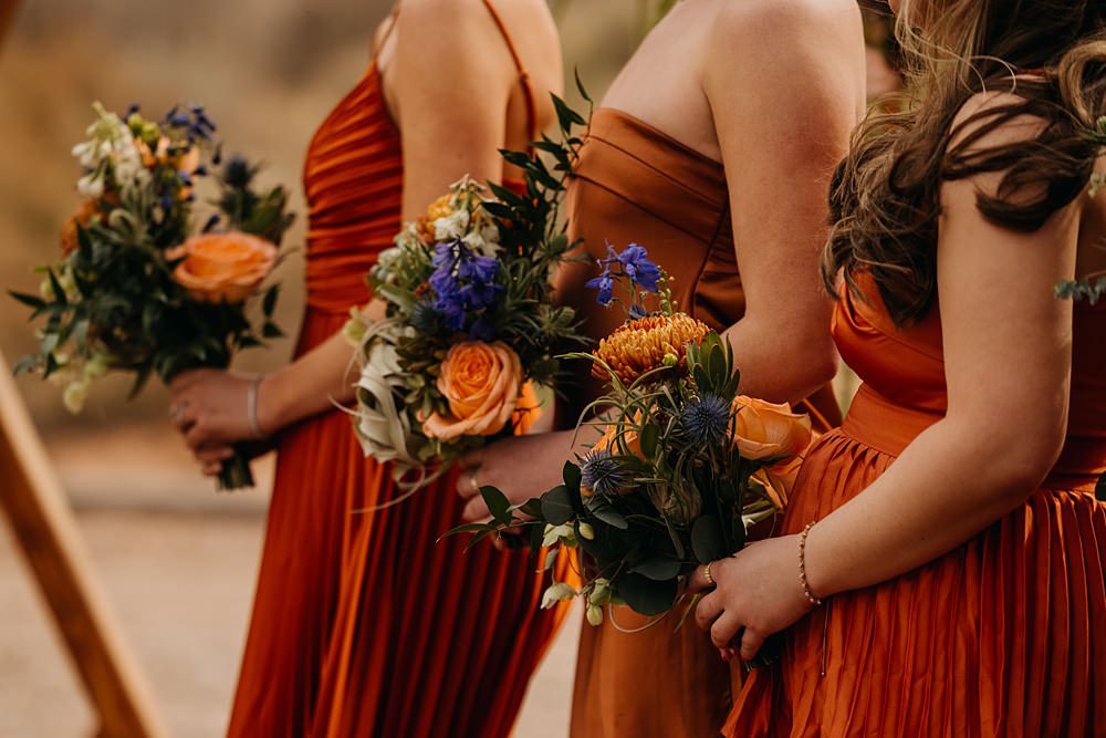 The Red Earth Venue Wedding Adventure and Vow Mismatched Orange Bridesmaid Dresses Bouquets